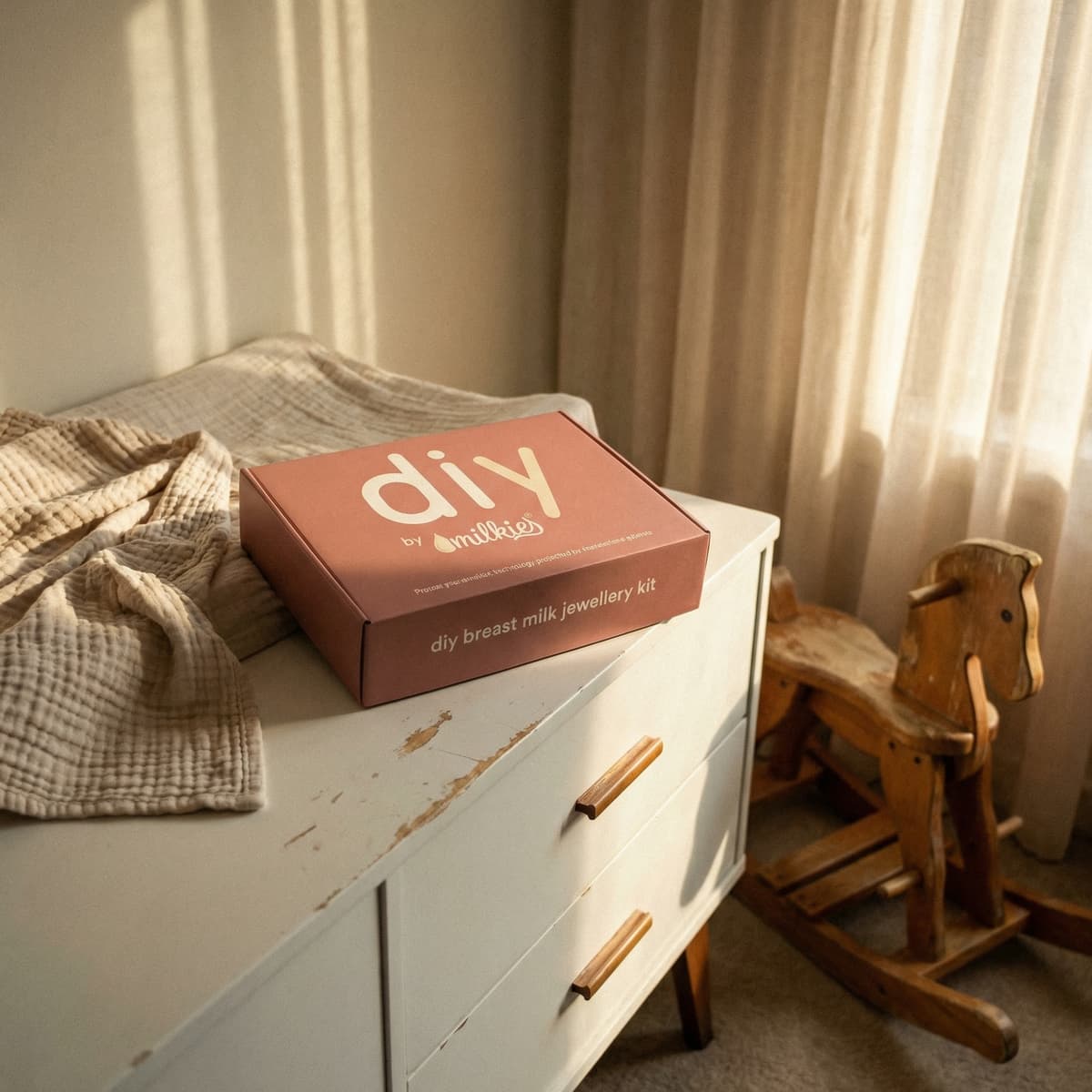 Scatola DIY by MILKIES per creare gioielli con latte materno su cassettiera bianca in cameretta dai toni caldi, idea regalo donna incinta originale e personalizzabile.