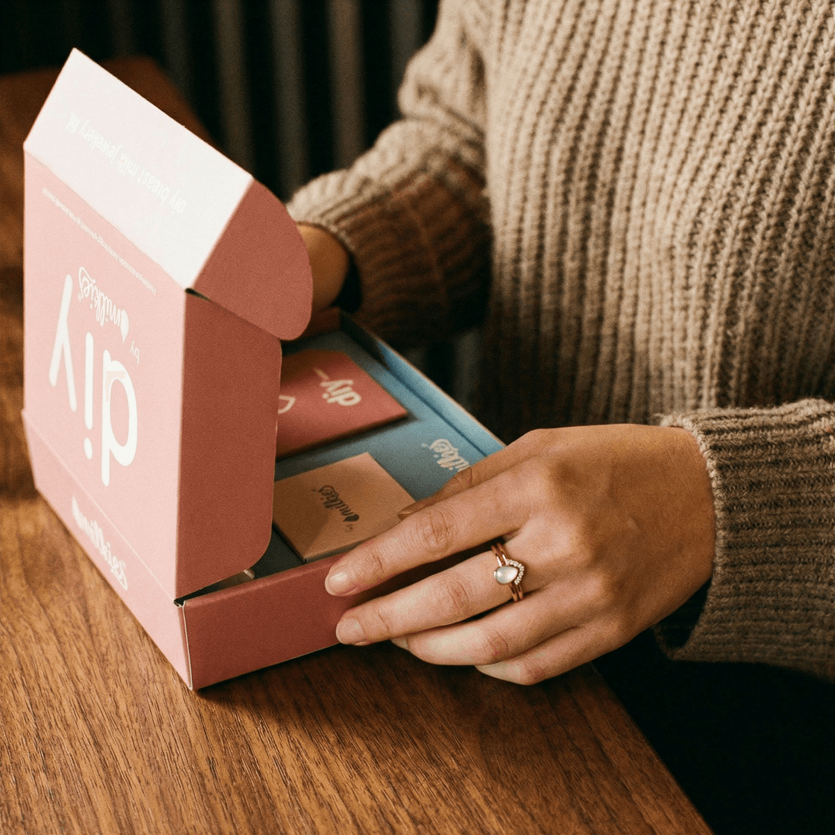 Kit fai-da-te DIY by MILKIES aperto su un tavolo mentre una mamma lo usa a casa indossando un anello, soluzione pratica e riservata per creare anelli latte materno e altri gioielli ricordo in autonomia.