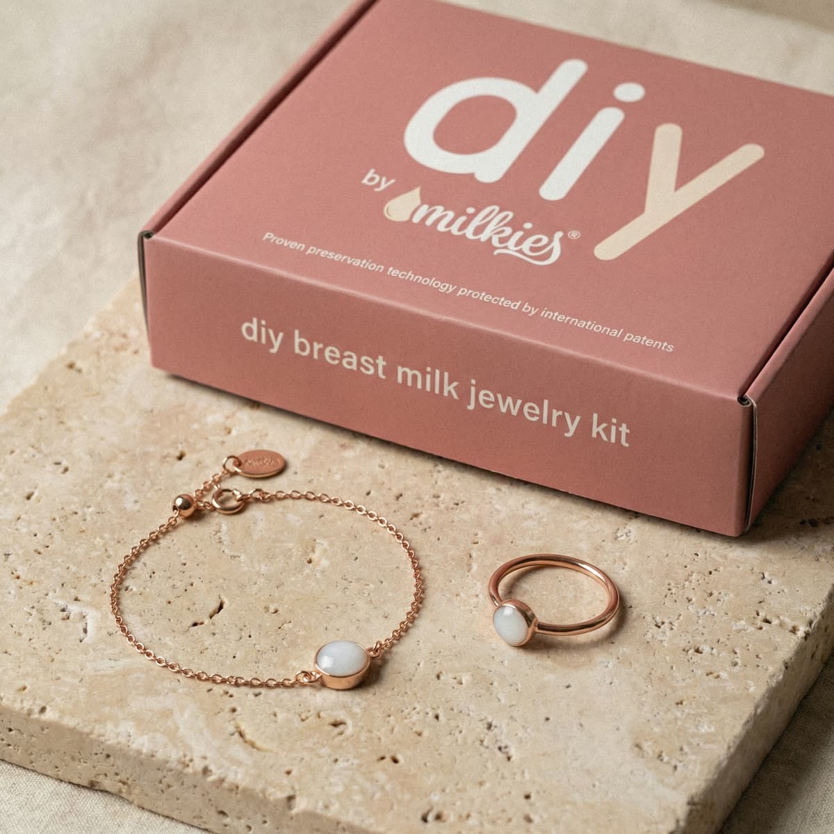 Confezione DIY by MILKIES con kit per creare bracciale latte materno, con bracciale e anello in metallo color oro rosa e pietra bianca su base in pietra.