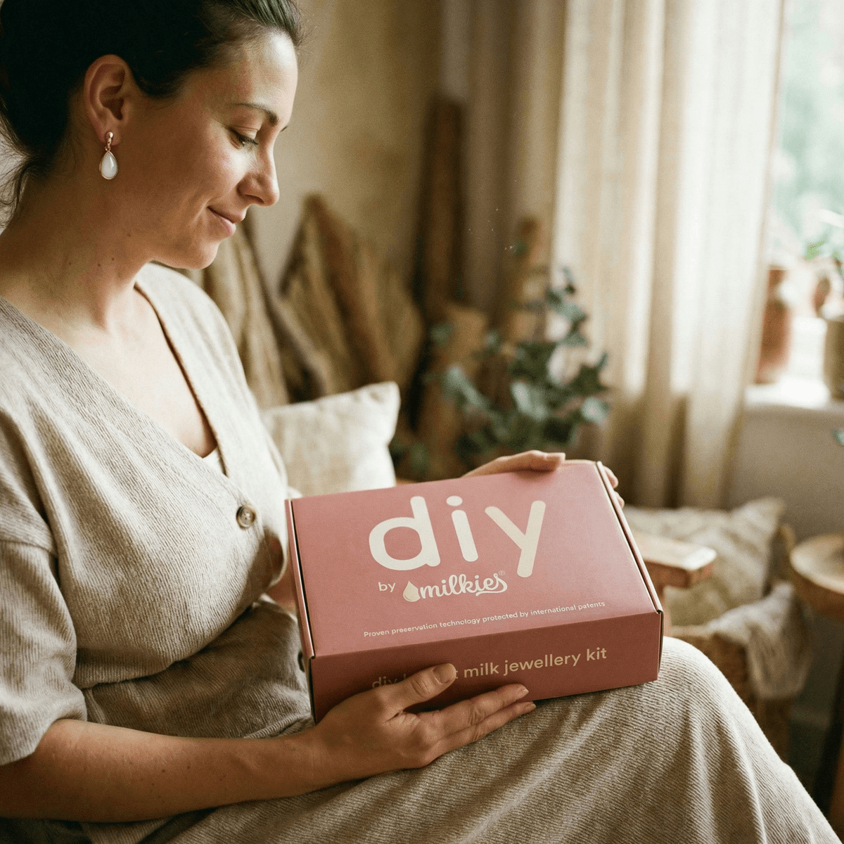 Donna che tiene in grembo il kit DIY by MILKIES, idea regalo svezzamento per creare a casa un gioiello ricordo con tecnologia di preservazione brevettata.