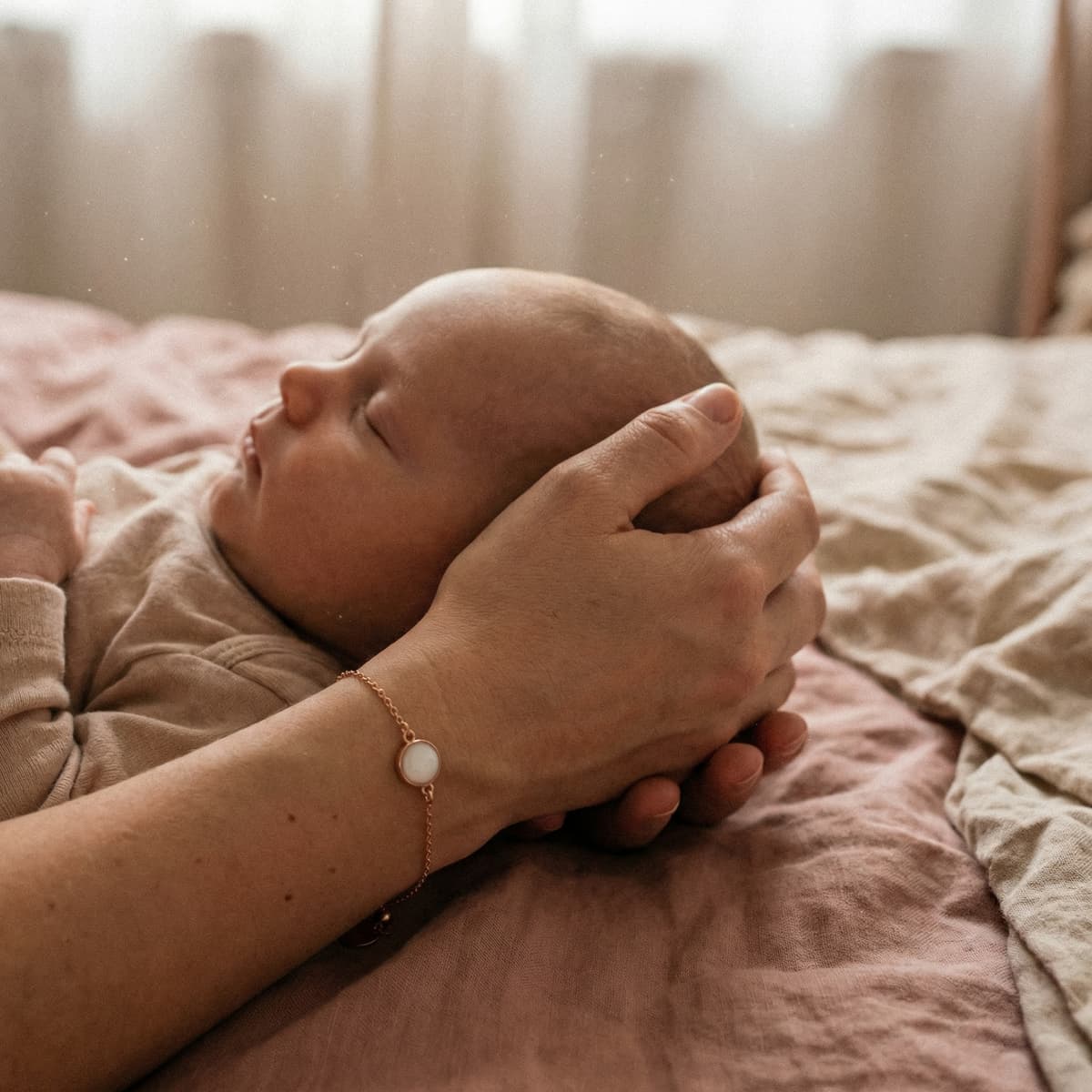 Neonato che dorme mentre la mamma lo accarezza indossando un bracciale ricordo: immagine che evidenzia perché scegliere un set creazione bracciale latte materno fai-da-te per conservare in modo intimo e personale un momento unico.